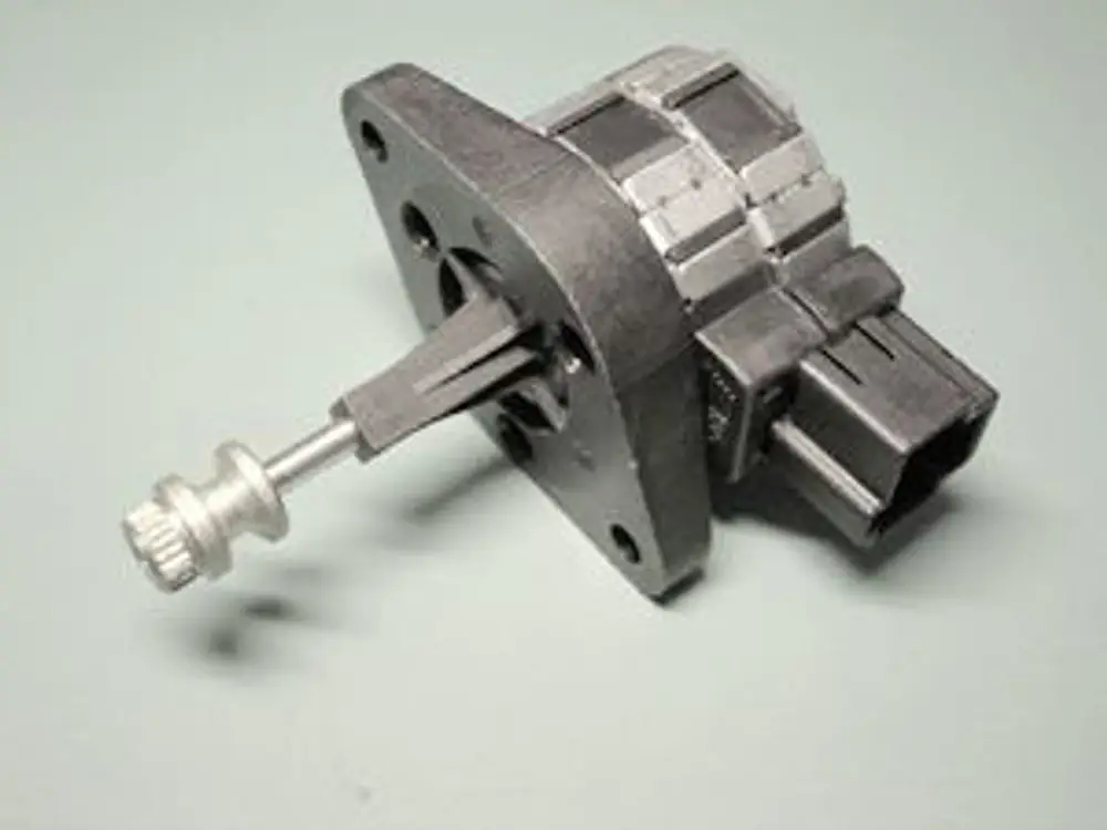 Schrittmotormodul von Remeha mit angebrachter Welle und elektrischem Anschluss. Das Bauteil hat eine quadratische Grundfläche und mehrere Befestigungslöcher.